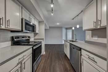 A modern kitchen with dark wood floors and white cabinetry. at Sunscape Apartments, Virginia, 24018